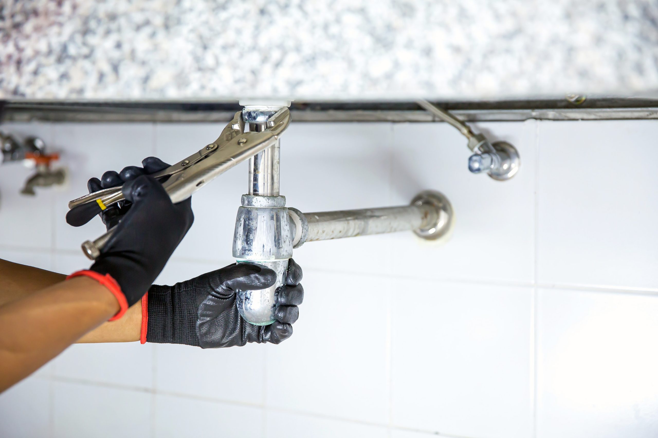 Plumber using a wrench to repair a water pipe