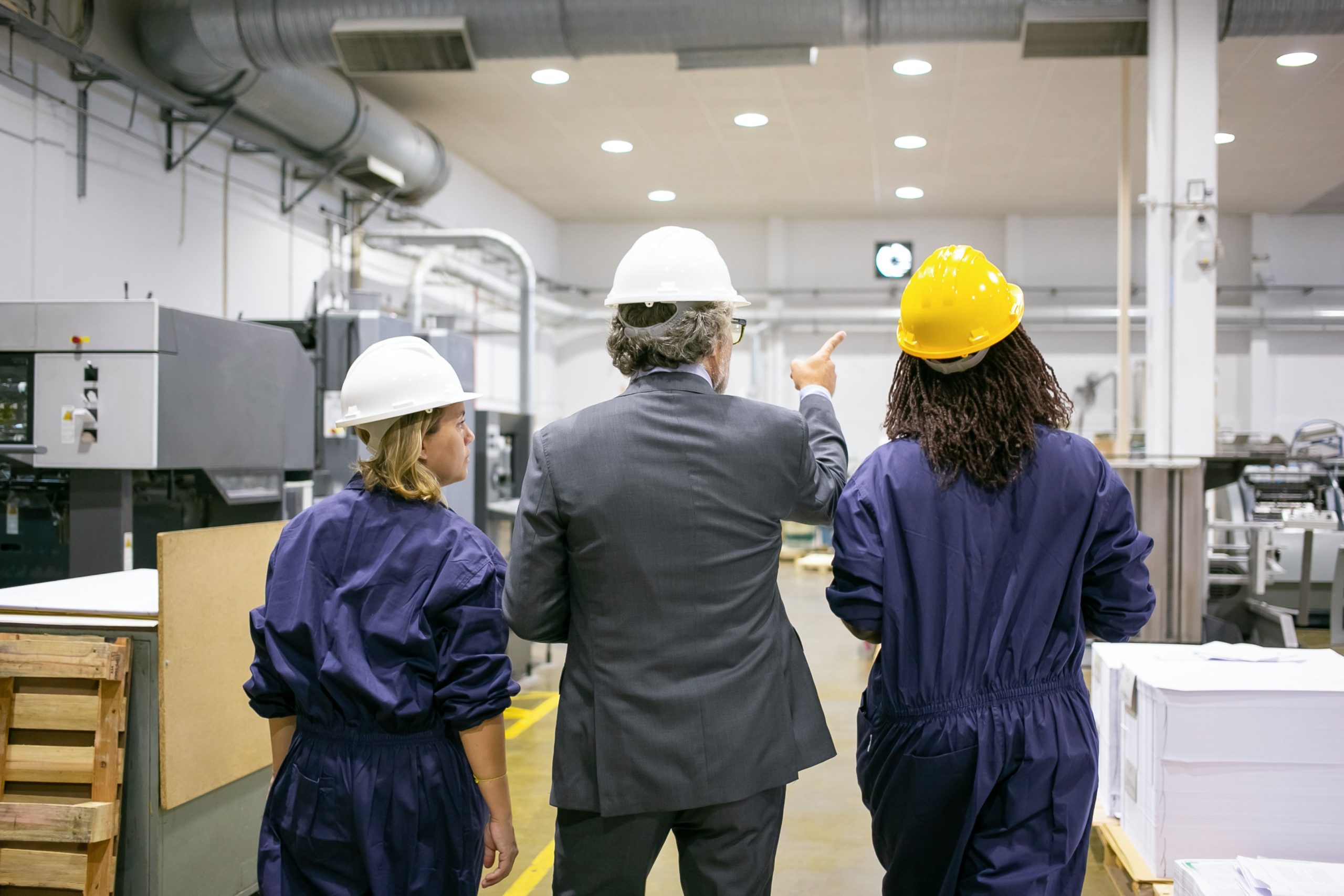 Supervisor and two workers inspecting equipment in an industrial facility
